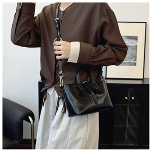 Détail du sac seau en cuir noir brillant avec garniture argentée et bandoulière