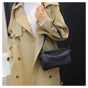 Detail of black lychee grain leather cylinder crossbody bag with metallic zipper closure