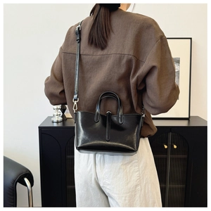Vue détaillée arrière d'un sac seau en cuir noir avec poignées et finitions argentées
