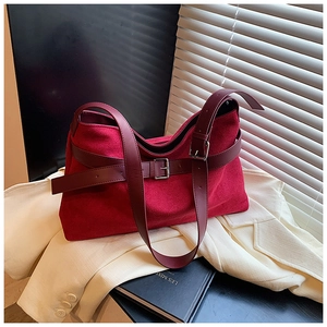 Vue détaillée du sac cabas en daim rouge avec lanières en cuir et boucles métalliques
