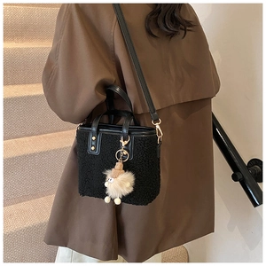 Detail of black faux shearling bucket bag with plush charm and detachable leather strap