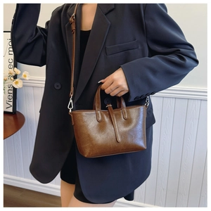 Gros plan d'un sac seau marron vintage porté avec un blazer bleu et une jupe