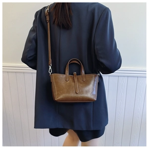 Détail du sac seau en cuir marron avec bandoulière sur un mannequin en blazer bleu