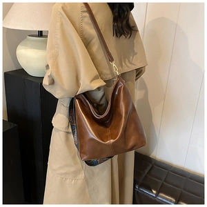 Brown oil-wax leather tote with ethnic strap detail shown on model in beige trench coat