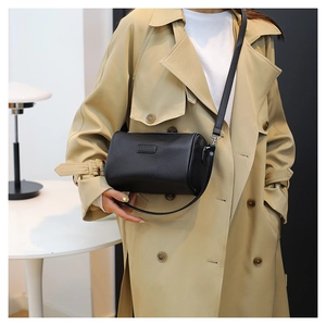 Litchi texture leather cylinder crossbody bag shown on a model in beige trench coat