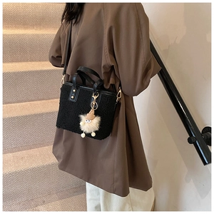 Detail of black faux shearling bucket bag with gold rivets and cute plush charm detail