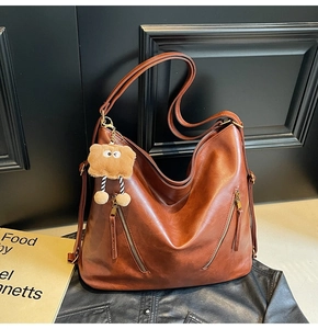 Detail of caramel brown Hobo bag with symmetrical zippers and cute plush bear charm