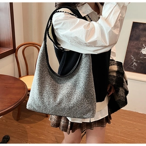 Detail of grey woolen crescent shoulder bag with black leather strap and textured fabric