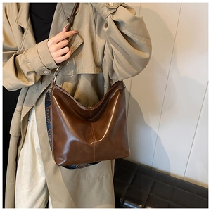 Detail of a dark brown glossy leather bucket bag with a colorful woven wide strap