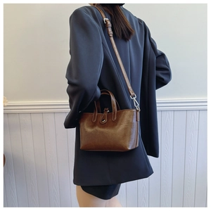 Détail d'un sac seau marron foncé avec texture grainée, doubles poignées et boucle argentée