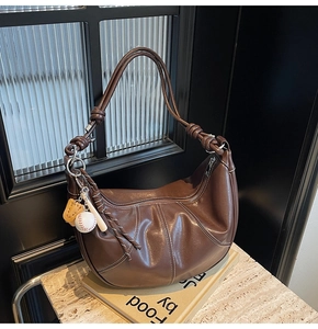 Detail of contrast stitching and leather knot on brown hobo bag with baseball charm