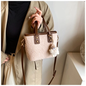 Detail of beige sherpa bucket bag with brown leather handles and monster charm