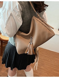 Brown pleated leather shoulder bag with tassels shown on a model for a stylish look