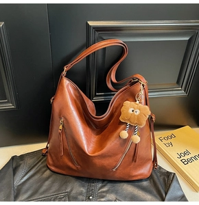 Close-up of deep brown lychee texture leather shoulder bag with decorative dual zippers