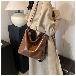 Detail of vintage brown hobo bucket bag with patterned wide strap and smooth finish