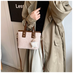 Detail of shearling bucket bag with leather strap and plush ball charm on a model