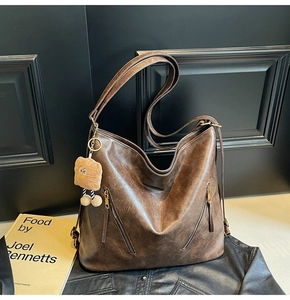 Macro shot of vintage brown leather tote bag texture with decorative zipper and plush charm