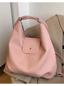 Bolso de mano plisado rosa de gran capacidad mostrado sobre fondo de blazer beige
