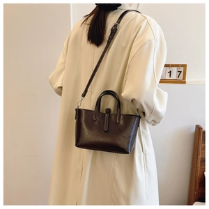 Sac seau marron foncé avec poignée et bandoulière réglable sur un mannequin