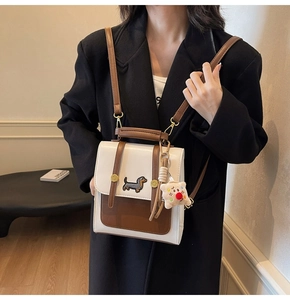 Detail of crossbody bag featuring dachshund embroidery and fuzzy charm on a chic model