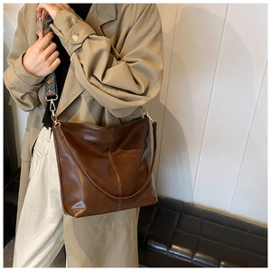Detail of vintage brown leather bucket bag with jacquard strap and polished finish