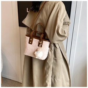 Detail of plush white fleece bucket bag with brown leather handles and gold metal hardware