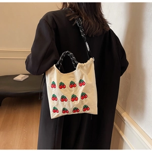 Detailansicht der cremefarbenen Segeltuchtasche mit Kirschstickerei und Kordelgriffen
