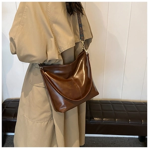 Detail view of large brown vintage bucket bag with ethnic jacquard strap on a model