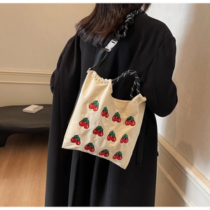 Detail der cremefarbenen Canvas-Tasche mit Kirschstickerei und verstellbarem Schultergurt