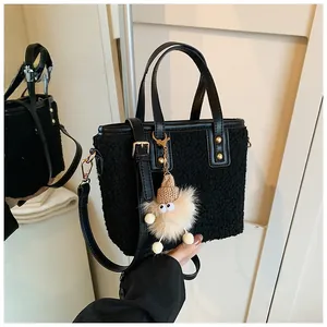 Detail of black plush bucket bag with leather trim and beige monster charm accessory
