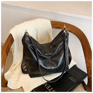 Detail of vintage black bucket bag with textured leather and patterned strap