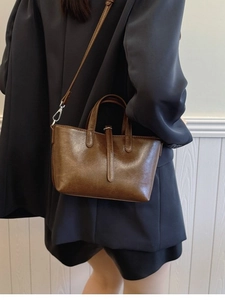 Sac fourre-tout rétro en cuir ciré marron porté par un mannequin au design trapèze