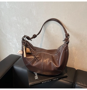 Close-up of brown hobo bag with contrast stitching and baseball themed keychain detail