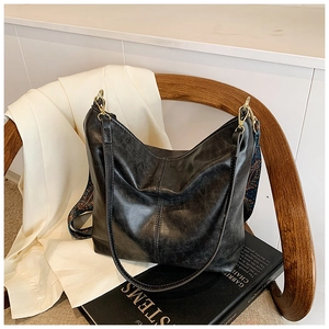 Detail of black vintage bucket bag with polished finish and ethnic woven strap