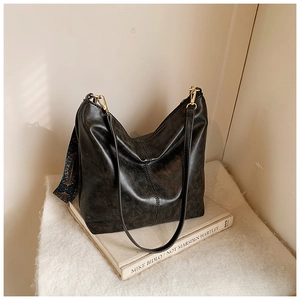 Detail of vintage black bucket bag with textured leather and ethnic pattern strap