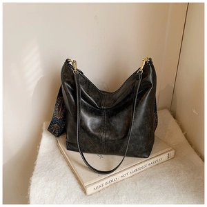 Detail of vintage black hobo bag with ethnic pattern wide strap and leather texture