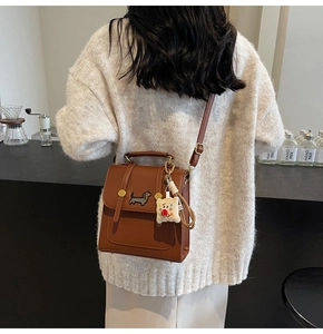 Detailed back view of a brown leather backpack featuring a cute dachshund embroidery patch