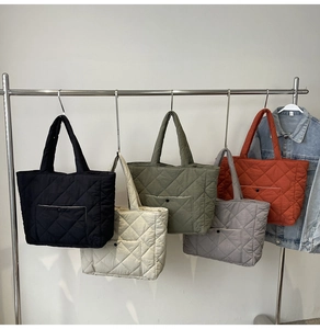 Quilted tote bags in five colors hanging on display rack with front pocket detail
