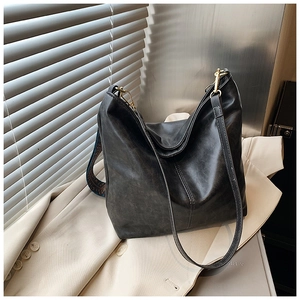 Detail of grey bucket bag with ethnic style woven strap on light blazer with light shadows