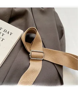 Detail of adjustable khaki canvas shoulder strap with smooth silver metal buckle
