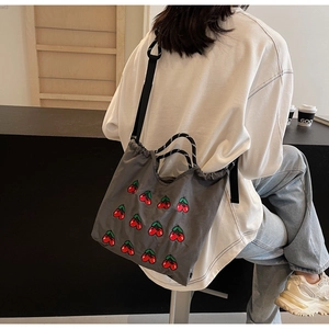 Detailaufnahme der gestickten Kirschen auf der grauen Canvas-Tasche mit Kordelzug