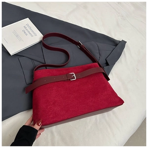 Détail du sac cabas en daim bordeaux avec boucle en métal argenté sur un blazer gris