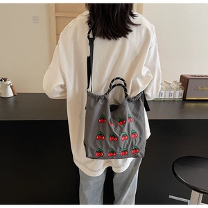 Detailansicht der grauen Canvas-Tasche mit Kirschstickerei und Webgriffen