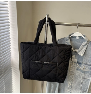 Close-up of black quilted puffer tote bag with front pocket and diamond texture