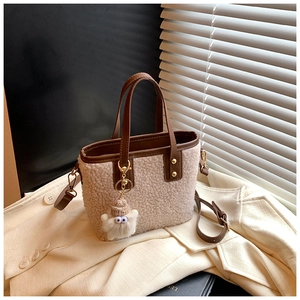 Detail view of lamb wool bucket bag with brown leather trim and cute plush charm