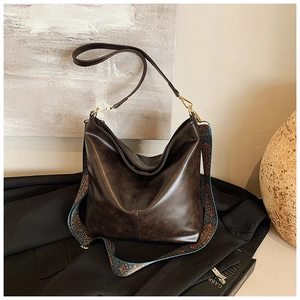 Deep brown vintage bucket bag with dual patterned and leather straps on blazer