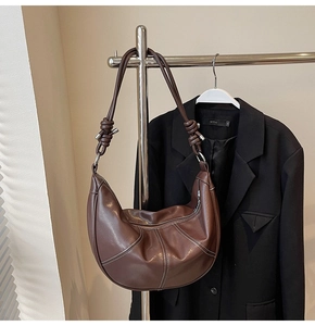 Close-up of brown leather hobo bag with contrast stitching and knotted strap detail