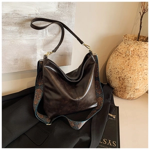 Detail of deep brown hobo bag featuring a geometric ethnic style canvas shoulder strap