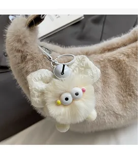 Detail of plush cream charm with bow and bell on a matching faux fur handbag