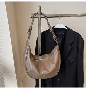 Detail of matte dark coffee leather crescent bag with pleated design and knotted strap